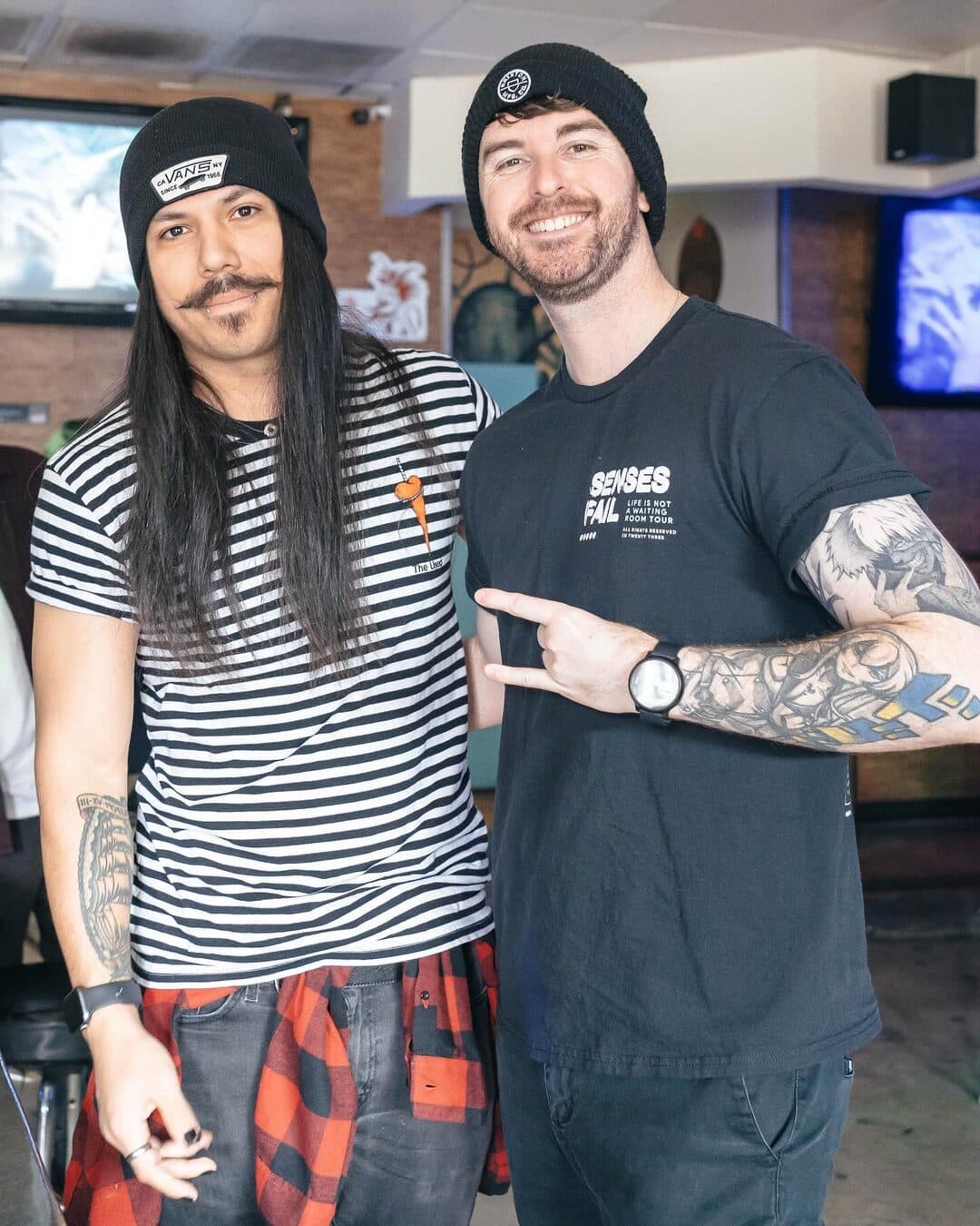 Two friends in black beanies, one in a striped shirt and a plaid flannel, posing together at the brunch